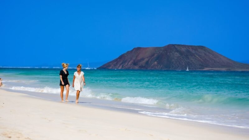 Women walking down beautiful beach in Corralejo, Spain