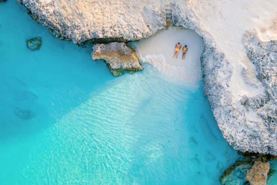 a couple of men and women on the beach of Tres Trap Aruba Caribbean Island. Tres Trapi Bay is popular with locals for snorkeling and diving in the turqouse colored ocean